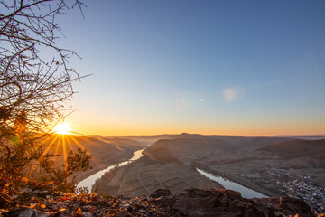 Sunrise over the Moselle. The river winds through a valley in a narrow loop surrounded by vineyards...