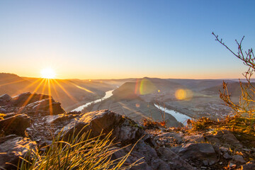 Sunrise over the Moselle. The river winds through a valley in a narrow loop surrounded by vineyards...