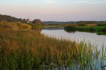 View of an ancient wooden windmill on the banks of the Sorot River on a sunny summer morning,...