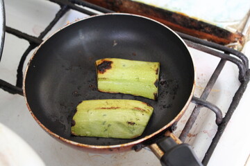 Two ripe avocado pieces sizzling in a frying pan, perfect for food and cooking-related themes.