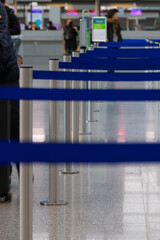 Metallic barrier poles with blue retractable belts in a row located in an airport terminal