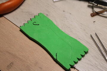 A green plastic fishing line winder with multiple fishing hooks attached. Commonly used by anglers...