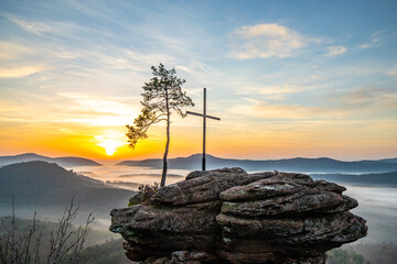 Sunrise over a mountain landscape. Rising sun behind a sandstone cliff in the forest. Fog forms in...