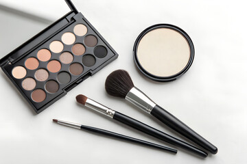 Minimalist beauty flat lay with an eyeshadow palette, two makeup brushes, and a round mirror — all placed on the right side of the composition.