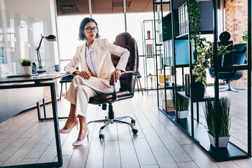 Elegant businesswoman in a stylish office chair, confidently seated in a modern workspace with...