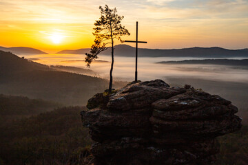Sunrise over a mountain landscape. Rising sun behind a sandstone cliff in the forest. Fog forms in...