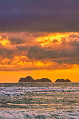 As the sun dips lower on the horizon, its warm, golden light can be absorbed and reflected by the black sand, intensifying the colors and creating a rich, deep contrast.