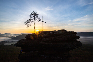 Sunrise over a mountain landscape. Rising sun behind a sandstone cliff in the forest. Fog forms in...