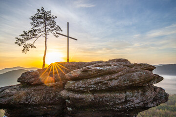 Sunrise over a mountain landscape. Rising sun behind a sandstone cliff in the forest. Fog forms in...