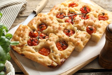 Cut delicious focaccia with tomatoes and spices on table, closeup