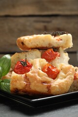 Pieces of delicious focaccia with tomatoes on table, closeup
