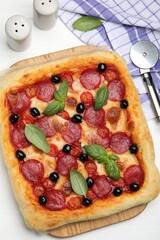 Tasty homemade pizza and cutter on white table, flat lay