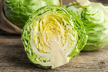 Obraz premium Fresh whole and cut cabbages on wooden table, closeup