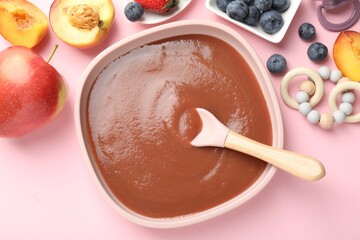 Baby food. Tasty puree in bowl, spoon, teether and ingredients on pink table, flat lay