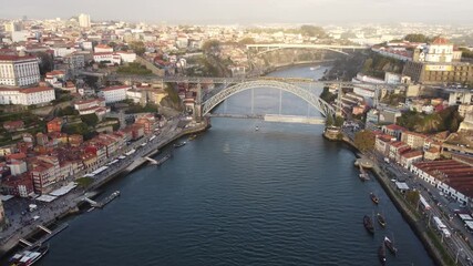 Porto, Portugal - October 21 2022 4K drone footage flying toward a bridge with the old town and boats on the river below on a warm autumn day