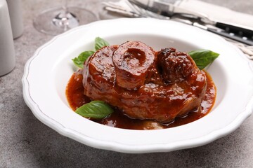 Traditional ossobuco dish with beef steak served on grey table, closeup