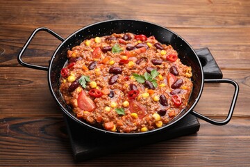 Tasty chili con carne in baking dish on wooden table, closeup
