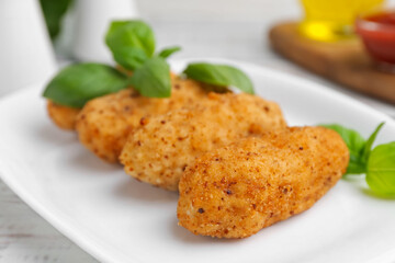 Tasty fried croquettes and basil on white wooden table, closeup