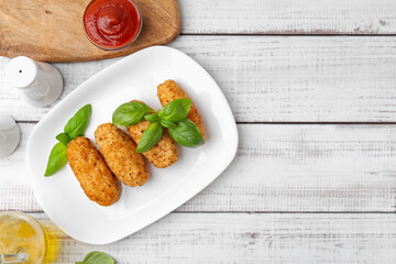Tasty fried croquettes, basil and sauce on white wooden table, flat lay. Space for text