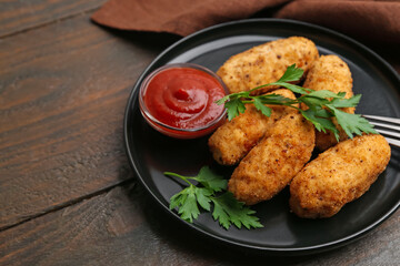 Tasty fried croquettes, parsley and sauce on wooden table, closeup. Space for text