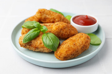 Tasty fried croquettes, basil and sauce on white tiled table, closeup