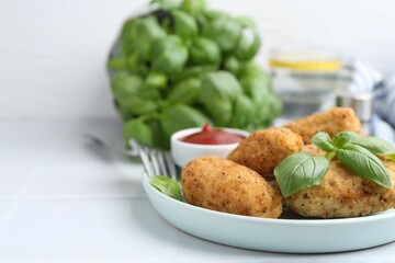 Tasty fried croquettes, basil and sauce on white tiled table, closeup. Space for text