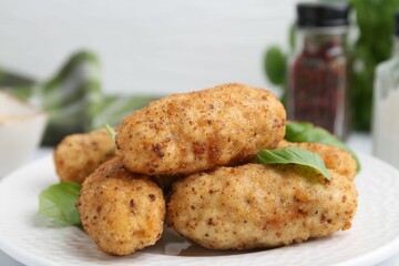 Tasty fried croquettes and basil on table, closeup