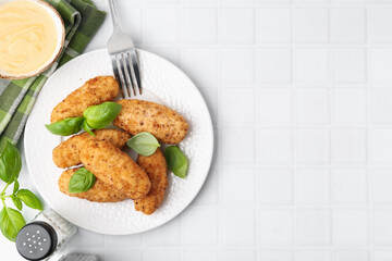 Tasty fried croquettes, basil and sauce on white tiled table, flat lay. Space for text