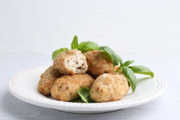 Tasty fried croquettes and basil on white textured table, closeup