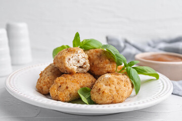 Tasty fried croquettes, basil and sauce on white textured table, closeup