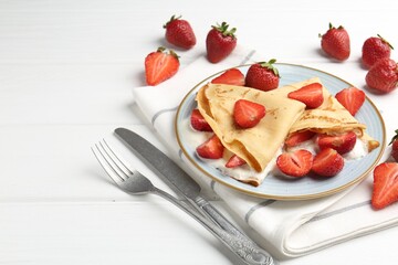 Delicious crepes with strawberries and cream on white wooden table, closeup. Space for text