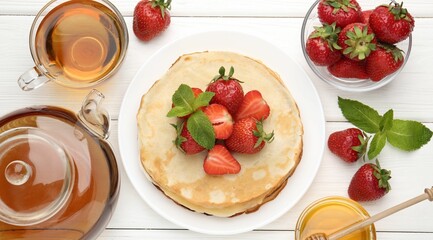 Delicious crepes with strawberries, honey, mint and tea on white wooden table, flat lay