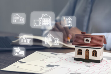 Real estate agent looking for housing indoors, closeup. Different buildings icons over table