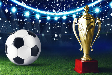 Football championship. Shiny golden trophy cup and soccer ball under falling confetti on stadium