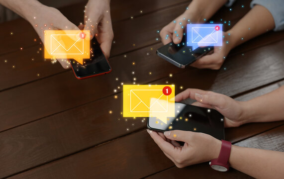 Email marketing, new message notification. People using mobile phones at wooden table, closeup