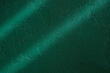 Dark green stucco wall with dramatic light and textured shadow lines