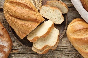 Cut bread loaf and spikes on wooden table, flat lay