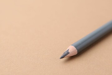 Grey eyebrow pencil on beige background, closeup. Space for text