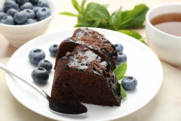 Pieces of delicious bundt cake with blueberries, mint, and chocolate shavings on table, closeup