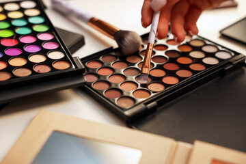 Woman with brush and eyeshadow palette at dressing table, closeup