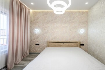 serene bedroom features a bed with a white comforter and a wooden headboard, flanked by textured...