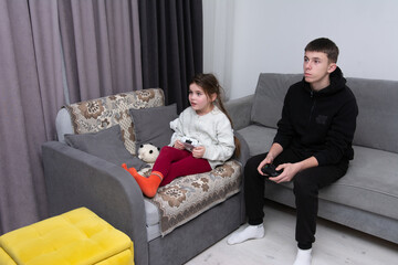 Sibling bonding time while gaming at home during a cozy winter evening, focused expressions and...