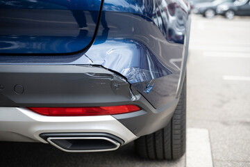dented rear bumper showing impact damage and scuff marks on dark blue vehicle exterior