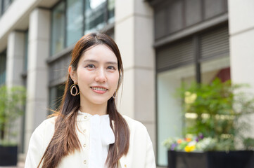 観葉植物の前で穏やかな微笑を浮かべる清潔感のある若い女性