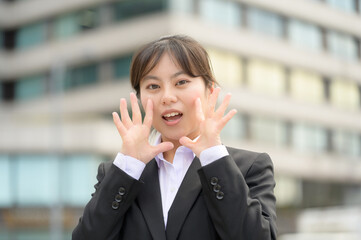 手を顔の横で広げて明るく元気にアピールするスーツ姿の新入社員