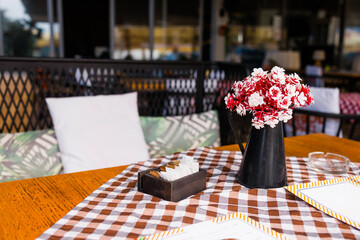 Relaxing summer cafe moment with soft cushions and flower decor. Concept of leisure, cozy atmosphere and outdoor holiday enjoyment.