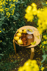 Fresh fruits and pastries on a table in a vibrant yellow flower field during springtime