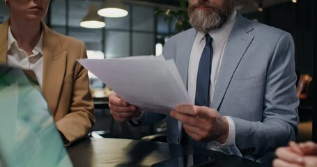 The boss shouts at his colleagues during a meeting in the office. He tears up the documents and throws the papers up