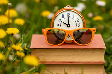 Alarm clock and sunglasses on books, back to school, morning wake up concept