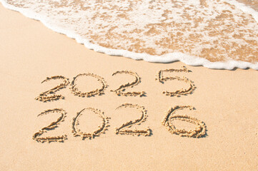 Inscription 2025 and 2026 numbers written on sand.  New Year 2025 replace 2026. Concept on the sea beach